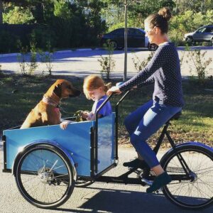 Una madre llevando a su hija y a su perro en una Cargobike